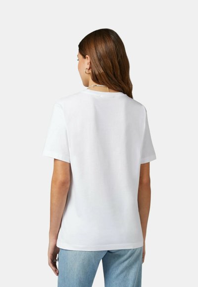 T-shirt bianco in cotone con scollo rotondo e maniche corte. Tessuto morbido, vestibilità rilassata, abbinato a jeans azzurri chiari.