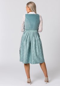 Teal dress with pleated skirt, textured material, and contrasting white lace sleeves. Adjustable back with a fitted bodice and floral pattern accents.
