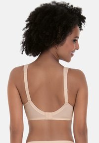 Beige bra with smooth fabric, adjustable straps, and a hook closure at the back. Rounded back design enhances fit and comfort.