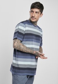 Trumpas rankovės dryžuotas T-shirt įvairiomis mėlynos spalvos atspalviais, su horizontaliomis skirtingo storio linijomis. Pagamintas iš minkštos medvilnės, su apvalia iškirpte.