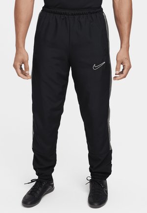 Black Nike joggers with an elastic waistband, side pockets, and gray accents along the sides. Smooth texture, tapered fit at cuffs.