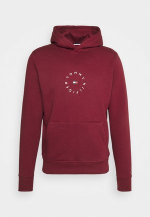 Bordowa bluza z kapturem, przednią kieszenią kangurką i okrągłym logo "Tommy Hilfiger" otaczającym flagę marki na środku klatki piersiowej.