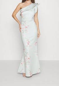 Yhden olkapään, muotoiltu mekko vaaleanmintunvärisenä, jossa on vaaleanpunaisia ja vihreitä kukkakuoseja. Silkkinen kangas, levenevä helma, yksityiskohtainen ruffla olkapäällä.