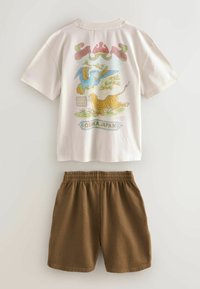 Chemise blanche à manches courtes avec un motif coloré de tigre et d'oiseau, texte "Osaka Japan", associée à un short marron à taille élastique.