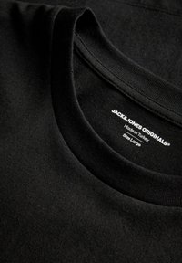 Μαύρο βαμβακερό t-shirt με στρογγυλή λαιμόκοψη, με ετικέτα "JACK & JONES ORIGINALS", κατασκευασμένο στην Τουρκία, μέγεθος Large, σε κοντινό πλάνο.