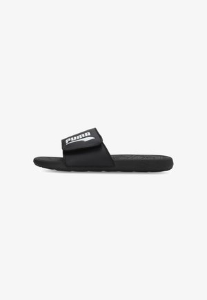Schwarze Puma Slide-Sandale mit verstellbarem Riemen und weißem Puma-Logo, strukturierter Innensohle und flacher Sohle.