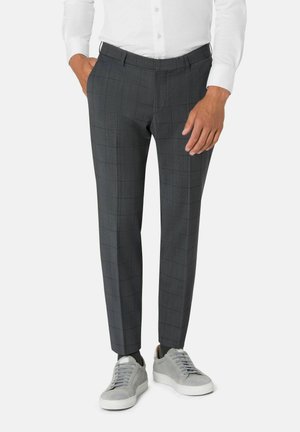 Grau kariertes Hosen mit strukturierter Oberfläche, im Slim Fit, mit Gürtelschlaufen und Seitentaschen, kombiniert mit hellgrauen Turnschuhen.