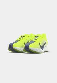 Bright yellow running shoes with mesh upper, navy accents, and a white sole. Features perforations and a raised heel for support.