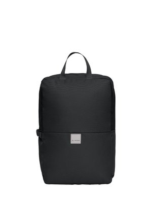 Sac à dos en tissu noir de forme rectangulaire avec poignée supérieure, boucle latérale et petit écusson logo sur le devant, présenté sur un fond blanc.