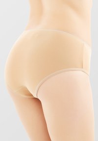 Mutande hipster in cotone beige con tessuto morbido, bordi senza cuciture e taglio a vita bassa, progettate per comfort e discrezione.
