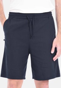 Pantaloni corti in cotone blu navy, cintura elastica con cordino, tasche laterali, lunghezza al ginocchio, texture liscia, design semplice, senza motivi.