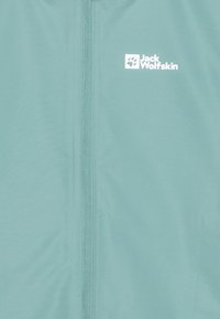Light blue Jack Wolfskin jacket with a smooth texture, front zipper, and white logo. The fabric appears lightweight and breathable.