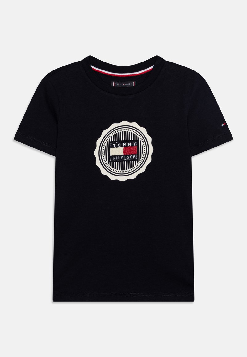 T-shirt in cotone nero con logo ricamato circolare caratterizzato da linee orizzontali e colori: rosso, bianco e blu, dettagliato con un bordo a onde.