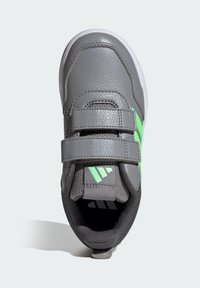 Zapatilla gris con dos correas ajustables de velcro, con acentos verdes y una parte superior texturizada. Ligera, con punta redondeada y suela de goma.