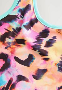 Šarena majica bez rukava s tie-dye uzorkom u ružičastoj, narančastoj i plavoj boji, s crnim uzorkom. Rubovi su obrezani svijetloplavom bojom. Mekani materijal.