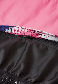 Funda de portátil rosa con un interior estampado que presenta puntos en blanco y negro. Textura suave, cierre con cremallera y "15" N" grabado en la banda.