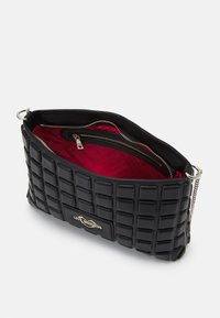 Black quilted handbag with a shiny finish. Interior is red with a zip pocket. Features a silver logo and chain for carrying.