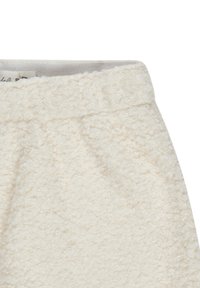 Textured cream-colored fabric with a soft, fluffy surface. Features a waistband with a smooth lining, accentuating the tactile design.
