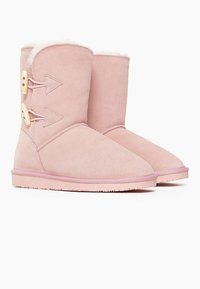 Botas de ante rosa hasta el tobillo con forro de piel sintética, dos cierres de toggles y suelas de goma texturizadas. Punta redondeada y acentos de diseño minimalistas.