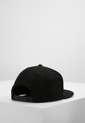 Czarna czapka snapback z regulowanym zapięciem, wystawiona na białym piedestale na jasnoszarym tle.
