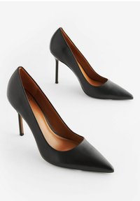 Tacchi alti in pelle nera con punta affusolata, design elegante e tacco stiletto. Texture liscia con fodera interna marrone.