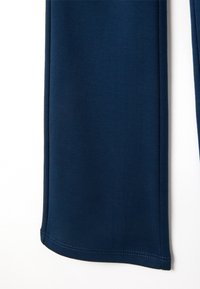 Marineblauwe sportbroeken worden getoond, gemaakt van een gladde, rekbare stof, met een aansluitende pasvorm en net afgewerkte zomen.