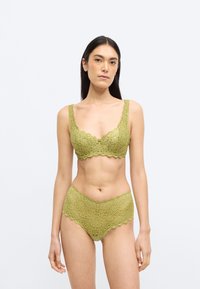 Pitsetega pesukomplekt summutatud rohelises toonis, millel on lainelised servad, keerukad mustrid ja pehme tekstuur. Komplektis on rinnahoidja ja sobivad aluspüksid.