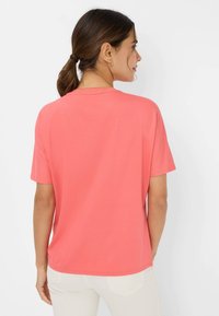 Coral short-sleeve t-shirt in soft cotton, featuring a rounded neckline and relaxed fit. Minimalist design without patterns or accents.