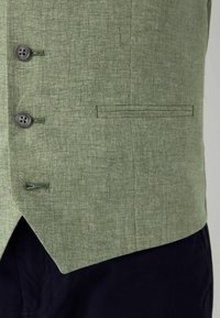 Green linen vest with a textured finish, featuring two grey buttons and a side pocket with a straight seam.