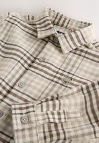 Camicia beige a quadri in tessuto morbido, con collo con bottoni, strisce marrone chiaro e scuro e due bottoni sul davanti.