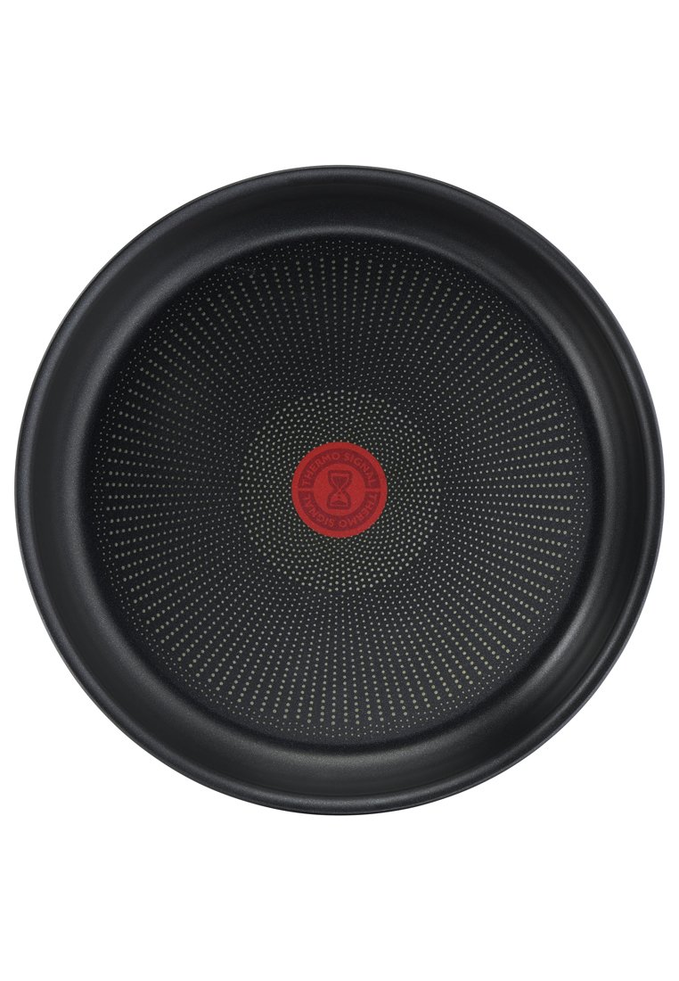 Schwarze runde Backform mit einer strukturierten Oberfläche, die in der Mitte ein rotes kreisförmiges Logo und ein gepunktetes Muster im Innenraum aufweist.