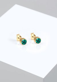 Boucles d'oreilles en or avec une pierre précieuse teal ronde au centre, finition polie, avec un design simple et épuré.