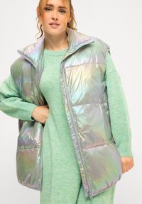 Iridescente gewatteerde vest met een hoge kraag, ritssluiting en oversized silhouet, gecombineerd met een bijpassende lichtgroene trui.