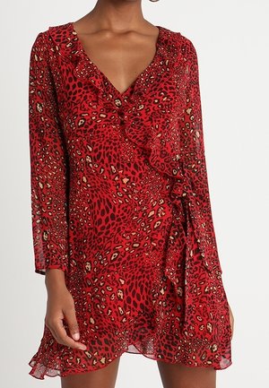 Vestito a portafoglio rosso con stampa leopardata, maniche lunghe, scollo a V e rifinitura arricciata, indossato da una persona su sfondo bianco neutro.