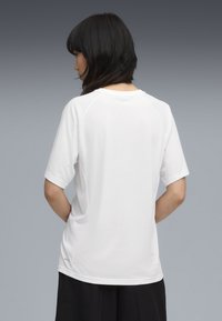 Hvid bomulds t-shirt med korte raglanærmer, rund hals og afslappet pasform. Bagsiden viser et simpelt design uden mønstre eller grafik.