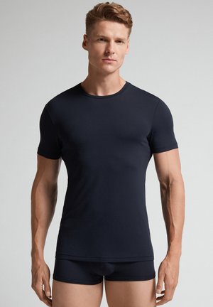 Marineblauwe T-shirt met korte mouwen, getailleerd ontwerp, gladde textuur, ronde halslijn. Draagt met bijpassende donkere onderbroek.