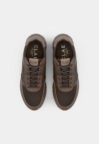 Brown mesh sneakers with contrasting brown accents. Features flat laces, a padded collar, and a textured rubber sole for traction.