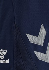 Marineblauwe sportshorts met een textuurpaneel, voorzien van een reflecterend zilveren pijlontwerp en een wit logo. Het materiaal lijkt lichtgewicht en ademend te zijn.