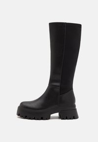 Black knee-high boots made of smooth leather, featuring a chunky rubber sole and a sleek design with minimal stitching and elastic panels.