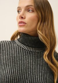 Sweter z golfem, dziergany w kolorze czarnym i jasnoszarym, z pionowymi paskami. Posiada wysoki dekolt i prążkowaną strukturę.