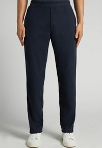 Námořnické modré teplákové kalhoty z měkké tkaniny, se rovný střihem, elastickým pasem a minimalistickým designem, spárované s bílými teniskami.