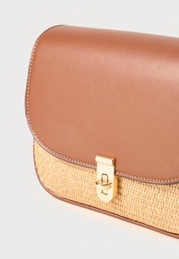 Borsa in pelle marrone con pattina sovrapposta a una base in paglia intrecciata, con chiusura in tonalità dorata e cuciture, finitura liscia e bordi arrotondati.