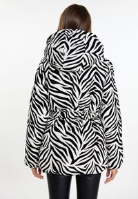 Veste à motif zèbre avec capuche, taille cintrée et texture matelassée en noir et blanc, vue de dos.