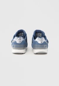 Kék sportcipők hasított bőr és hálós felsőrésszel, ezüst díszítésekkel és fehér talppal. A sarkon logóval és az oldalukon csíkozott mintával.