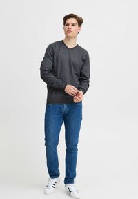 Donkergrijze langarmige V-hals trui, getailleerd ontwerp, lichtgewicht stof. Draag met blauwe spijkerbroeken en witte sneakers met zwarte strepen.