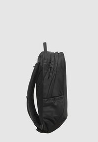 Zaino nero caratterizzato da un design slanciato, zip, dettagli in rete e una tasca laterale. Realizzato in tessuto resistente con finitura opaca.