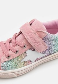 Sneaker rosa con accenti glitterati verdi e viola, caratterizzata da un dettaglio a stella bianca e una fascia in Velcro sopra i lacci. Materiale in tessuto morbido.