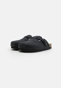 Grå klumper med rund tå, justerbar spenne og svart gummisåle. Har myk fôr og minimalistisk design.