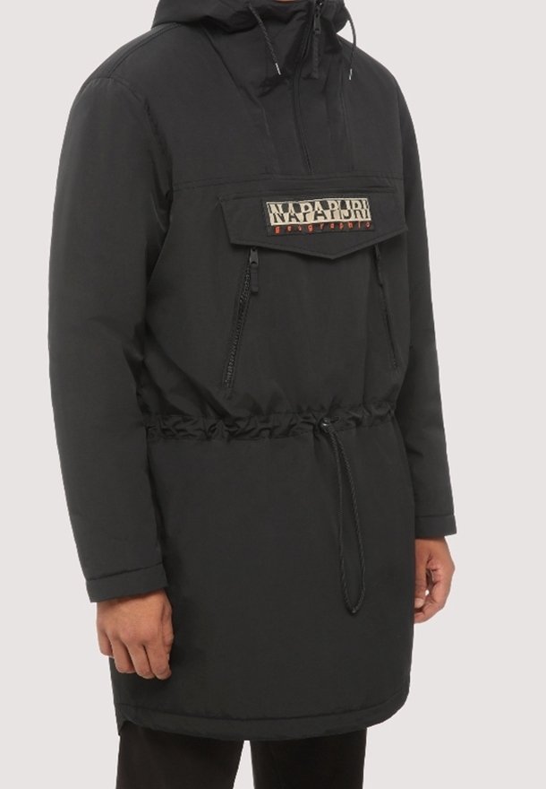 Anorak noir à capuche avec poche avant zippée, poche à rabat avec logo Napapijri, et cordon de serrage réglable à la taille, porté par une personne.