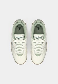 Un par de zapatillas blancas y verde claro con cordones, texto "Flight" en la lengua y logotipo Jumpman en negro en las plantillas, vistas desde arriba.